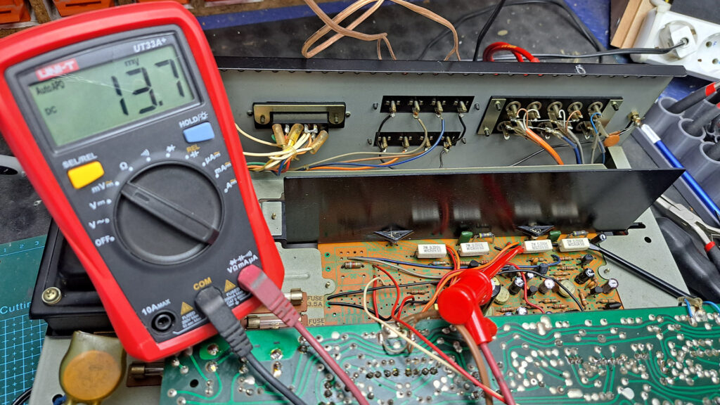 Placa interior do Amplificador Sansui AU-2900 a ser regulada a nível de tensão por um MULTÍMETRO UNIT-T vermelho e preto